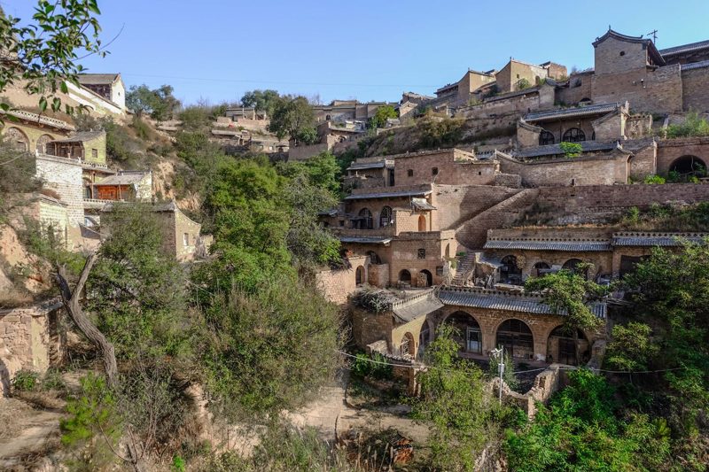 The village of Lijiashan, China — tiered stone cave houses with carved wooden facades built into a steep hillside