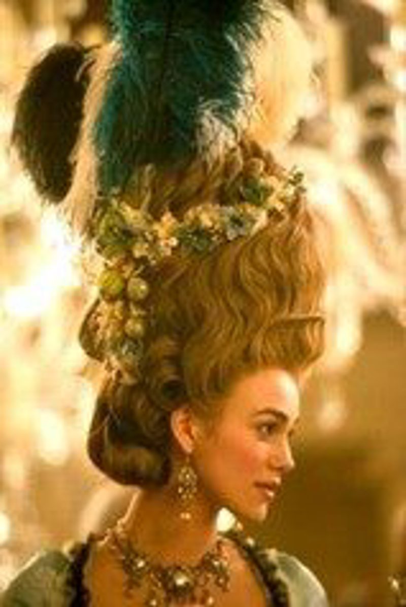 An elaborate 18th-century powdered wig piled high and dressed with feathers and flowers