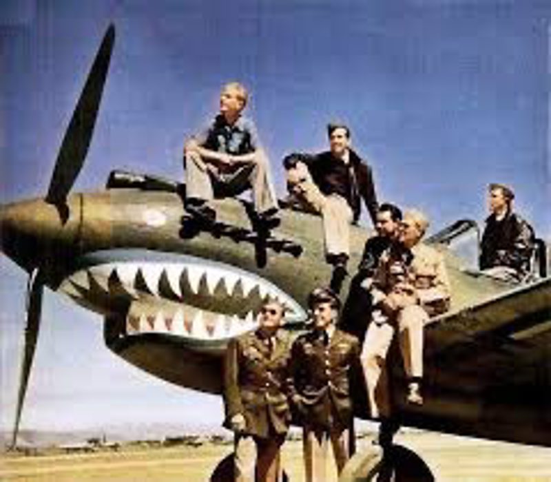 Second World War Flying Tigers aircrew posed on the wing and nose of a shark-mouth P-40 fighter