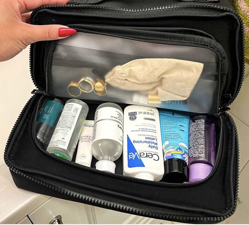 An open toiletries case packed upright with full-size bottles, tubes and jars